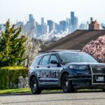 Seattle police vehicle with skyline and cherry blossoms in background.